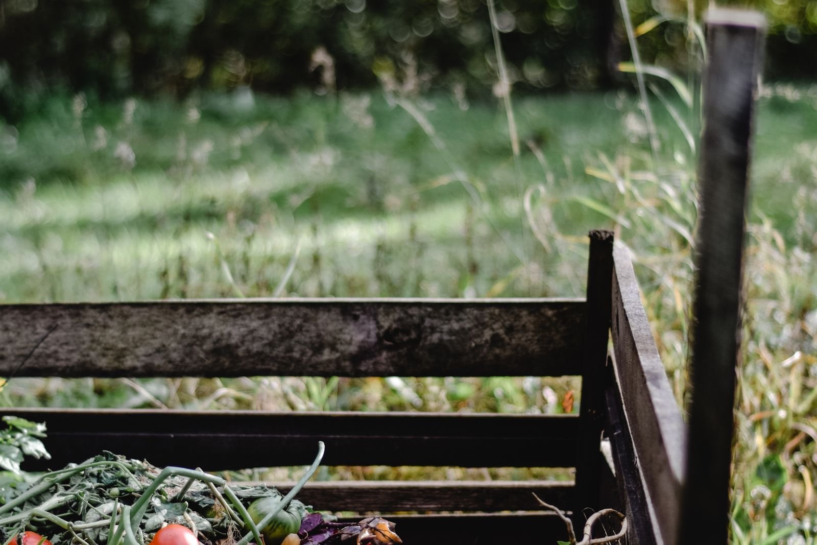 Bac à compost en bois rempli de déchets verts au jardin