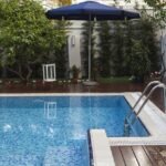 Piscine bordée d'une terrasse et d'un jardin aménagés devant une maison contemporaine