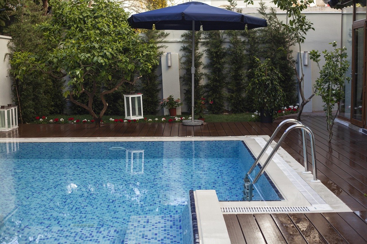 Piscine bordée d'une terrasse et d'un jardin aménagés devant une maison contemporaine